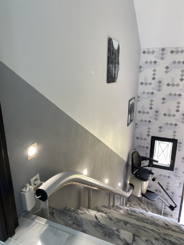 Monte-escalier courbe installé sur un escalier en marbre en train de monter